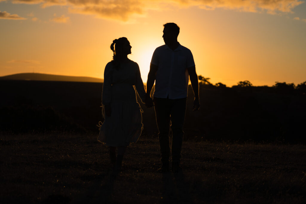 A couple holding hands in silhouette at sunset