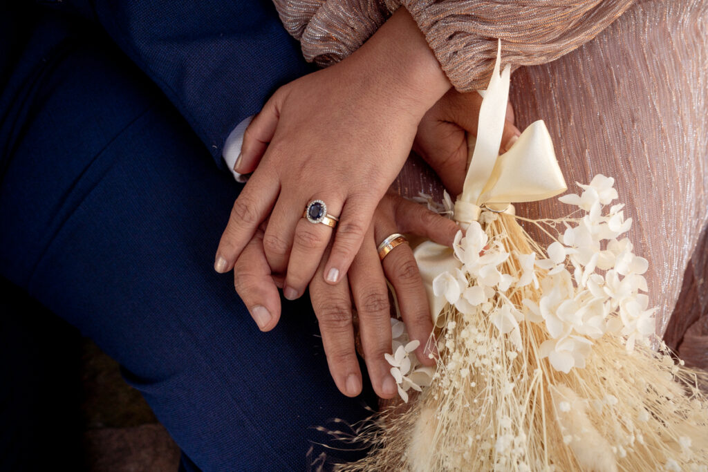 Close-up of a couple's hands, wedding rings and dried flowers
