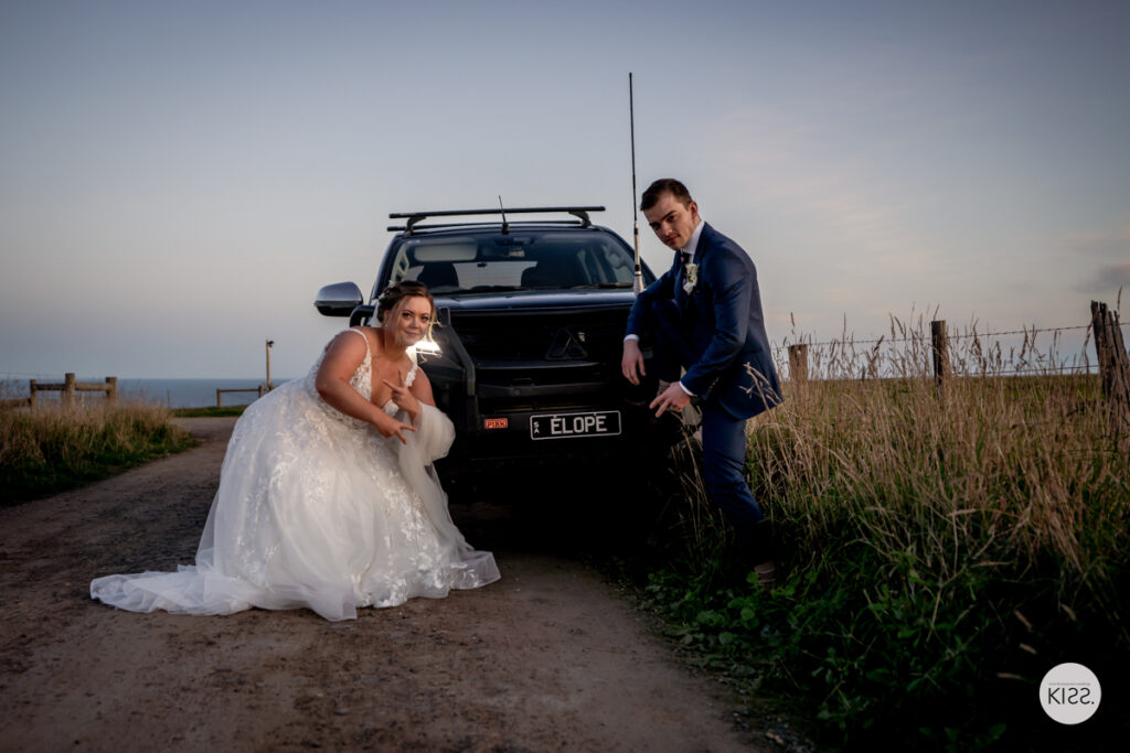 A wedding couple beside a four-wheel-drive vehicle