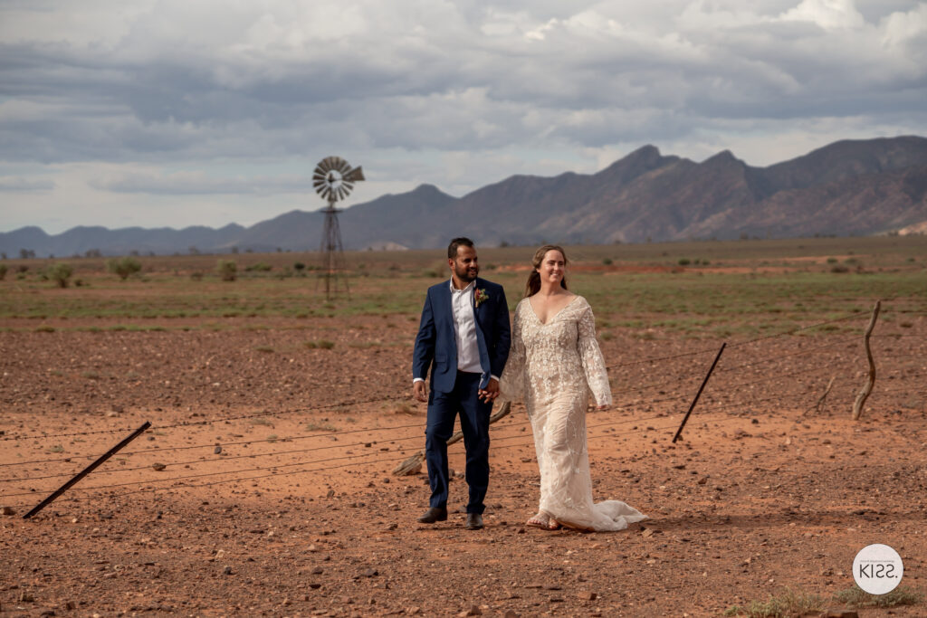 A wedding couple walking along a red dirt track