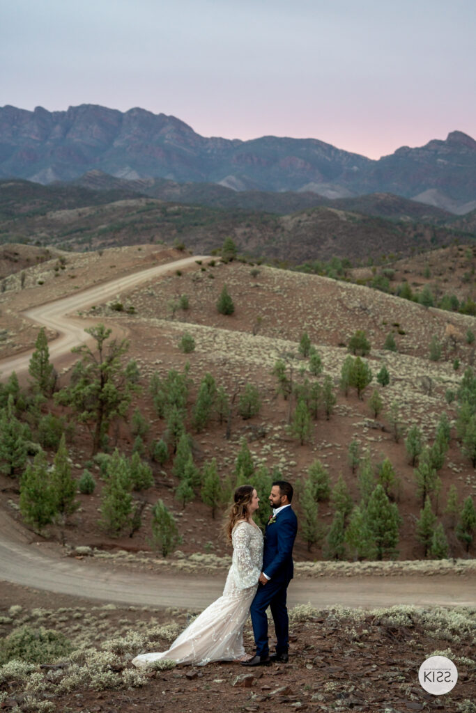 A wedding couple on a hillside overlooking the ranges