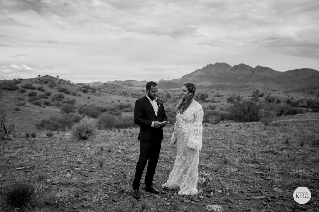 A couple exchanging vows in an open landscape in black and white