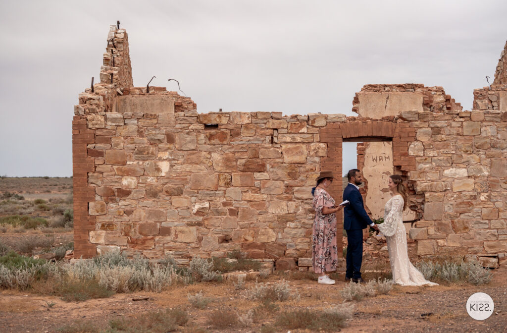 A small wedding ceremony beside a ruined stone building