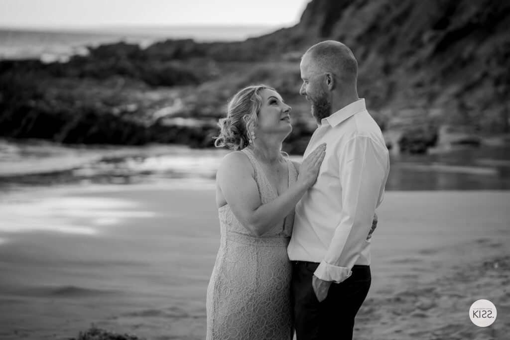 A couple smiling together beside the sea in black and white