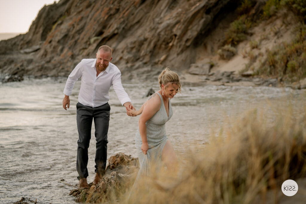 A couple walking hand in hand through shallow water