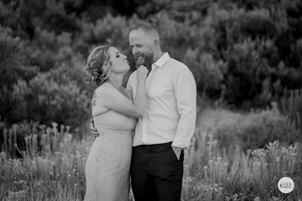A couple embracing among coastal plants in black and white