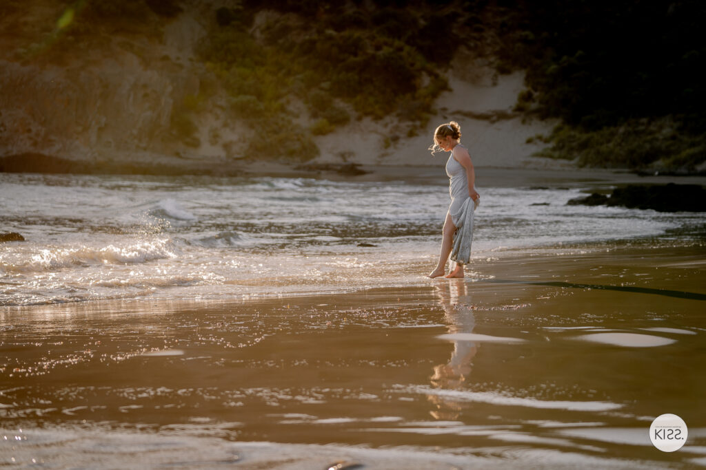 A bride walking through shallow water at the beach