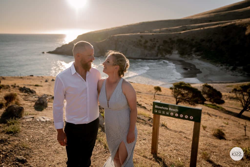 A wedding couple standing beside a beach walking track