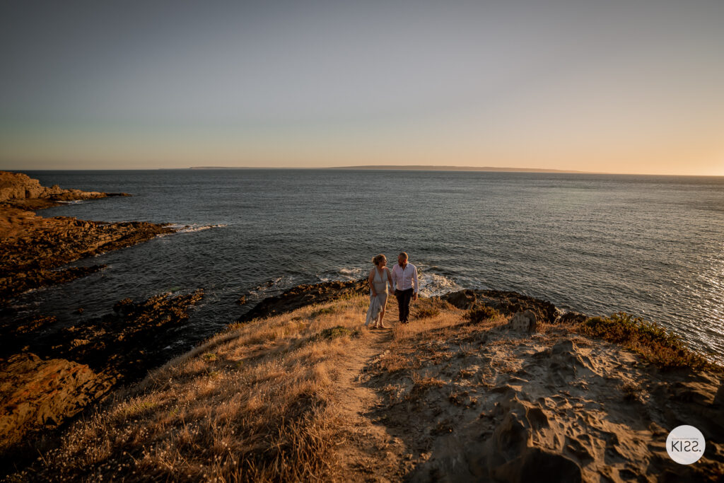 A wedding couple on a rocky headland above the ocean