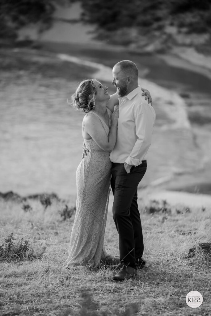 A wedding couple embracing above the beach in black and white