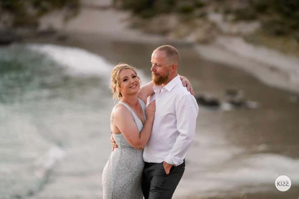 A wedding couple smiling together above Blowhole Beach
