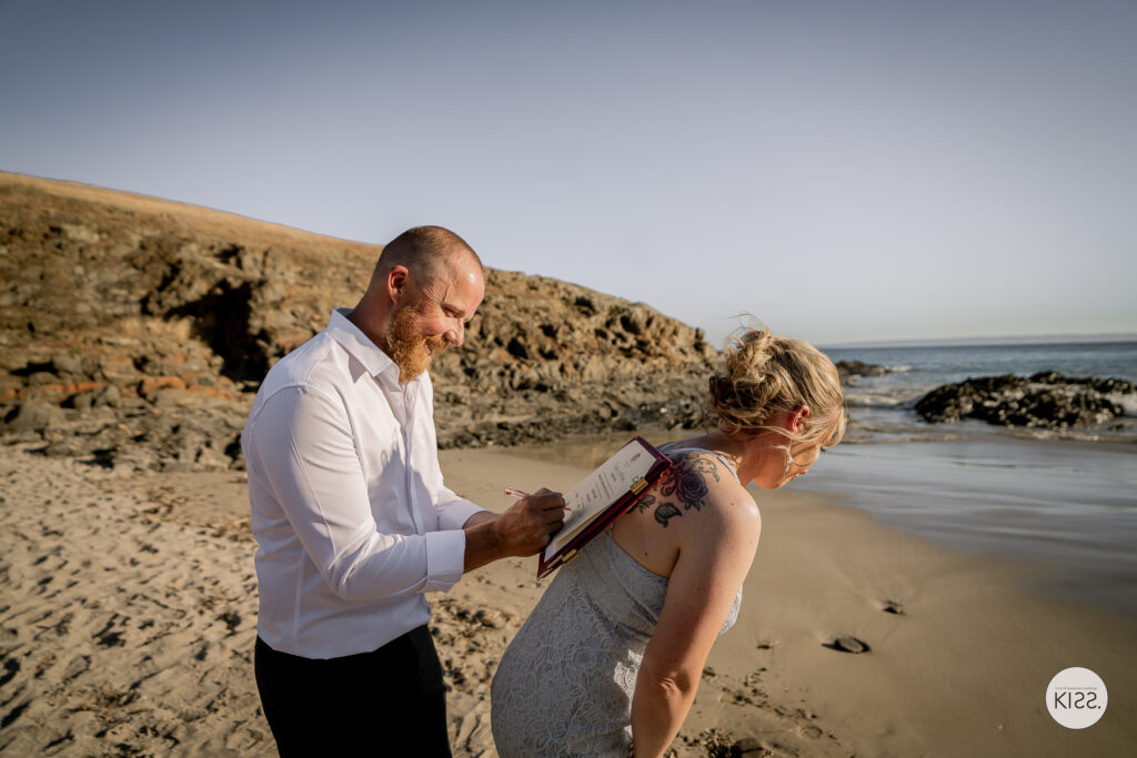 A groom signing the marriage register resting on his bride's back
