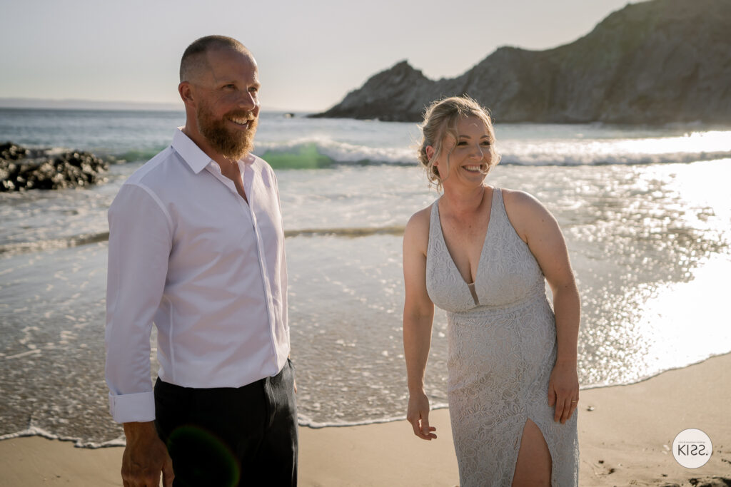 A newly married couple standing together on the beach