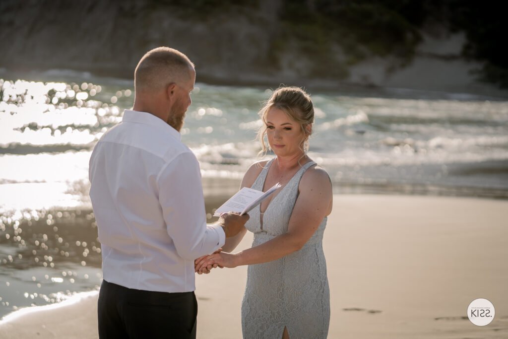 A couple holding hands during their beach wedding ceremony