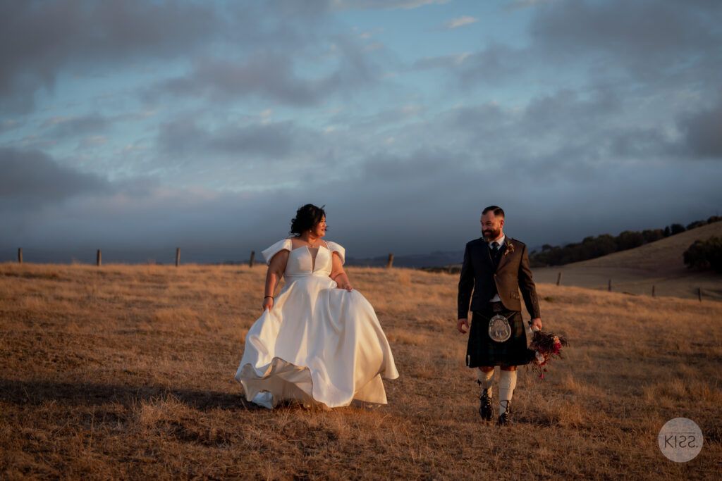 A wedding couple walking towards each other across a dry field