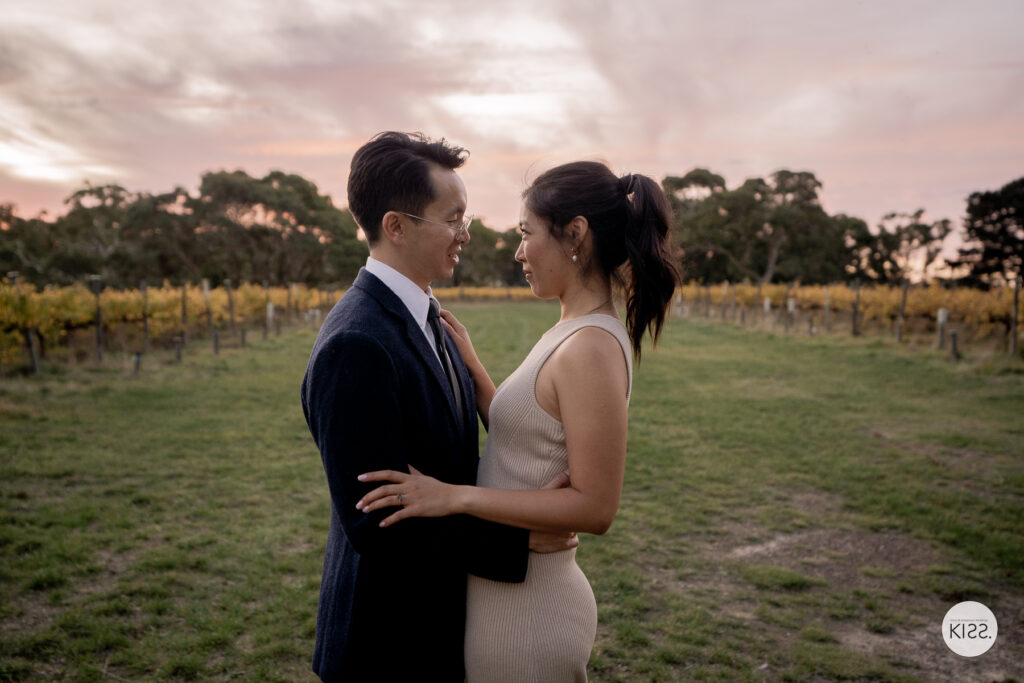 A couple embracing beside a vineyard at dusk