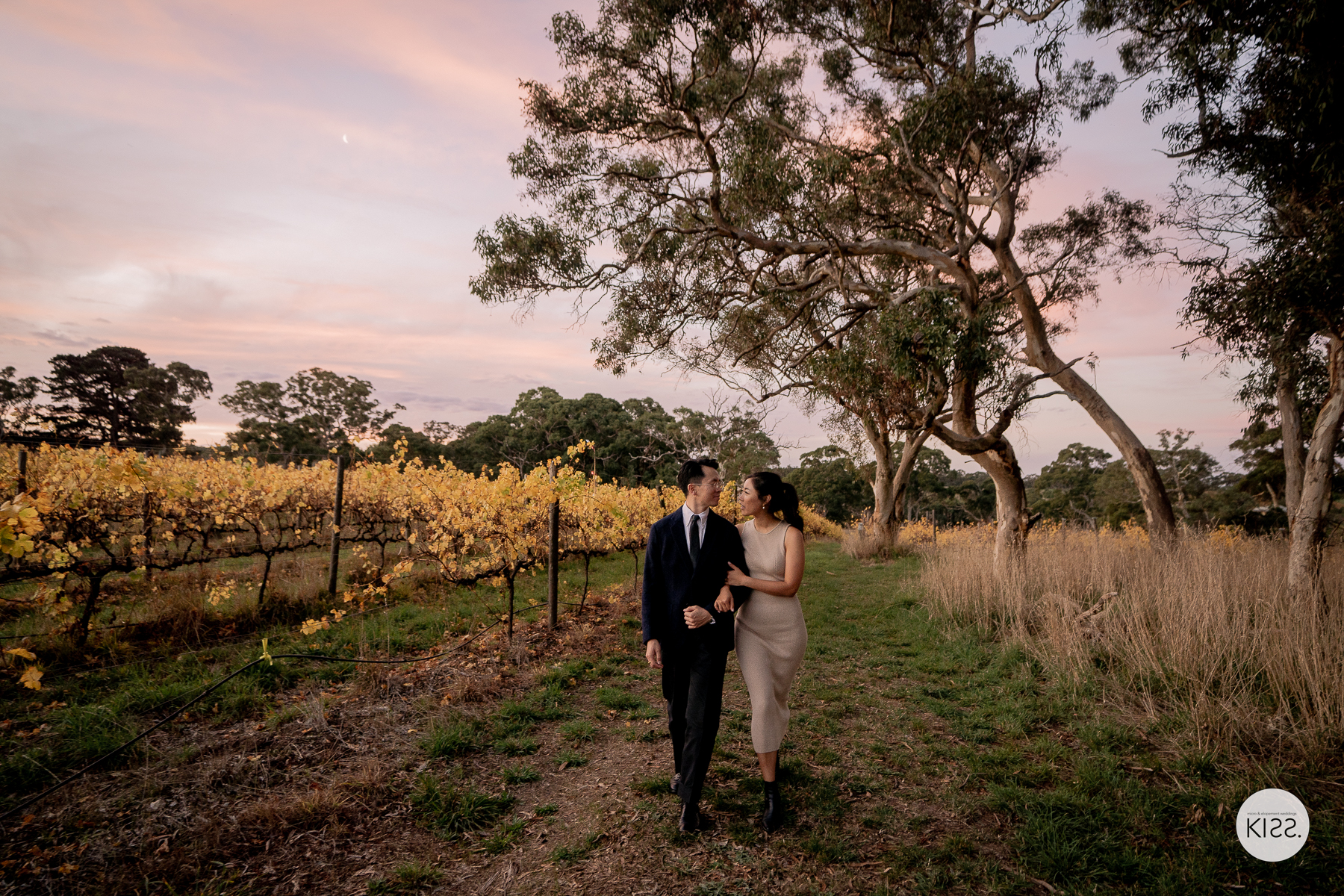 Bride and groom walking through Clare Valley vines after their wedding ceremony