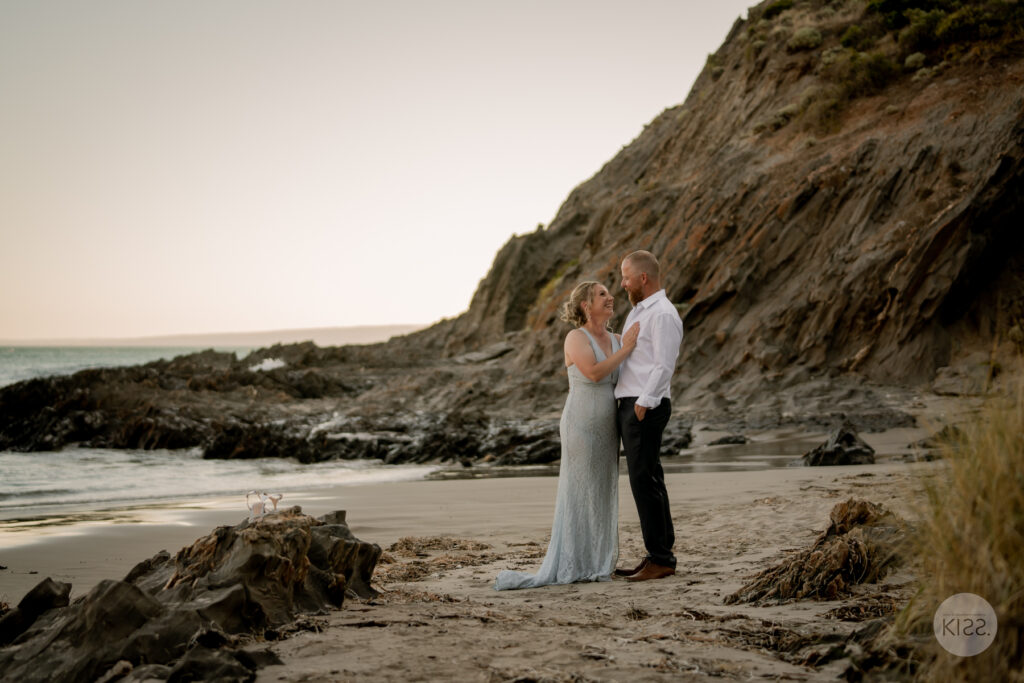 A wedding couple embracing at a rocky cove