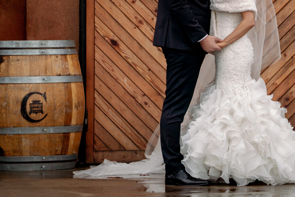A wedding couple standing beside a wine barrel and timber wall