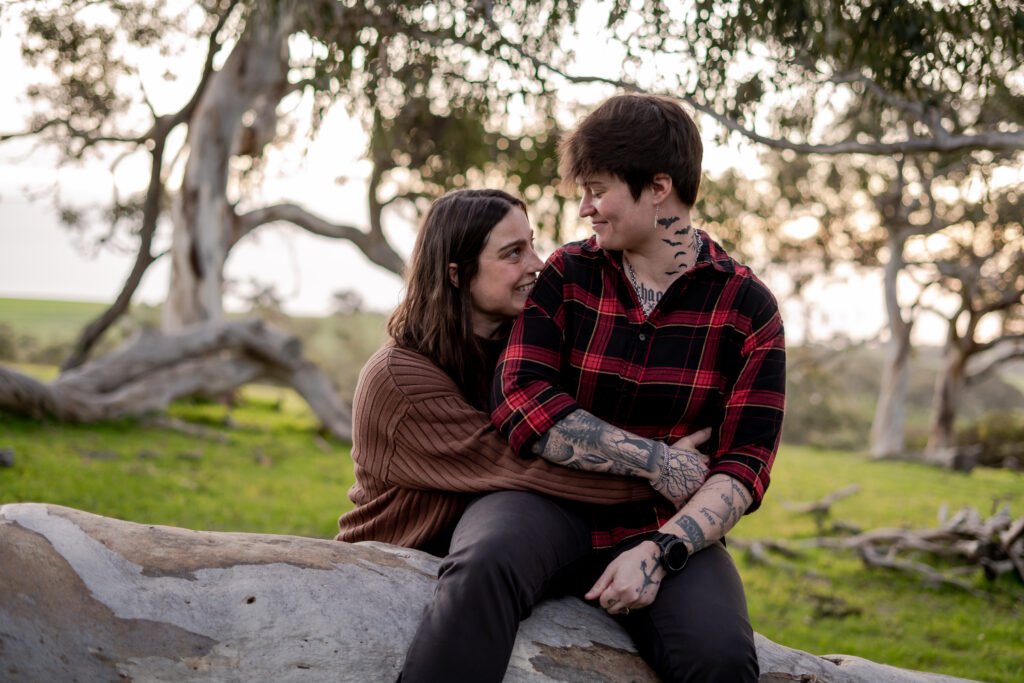 A couple sitting together on a fallen tree during an engagement session