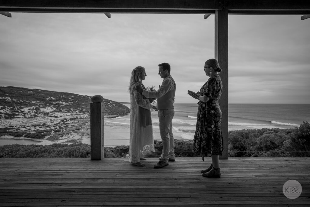 A small wedding ceremony on a coastal deck in black and white