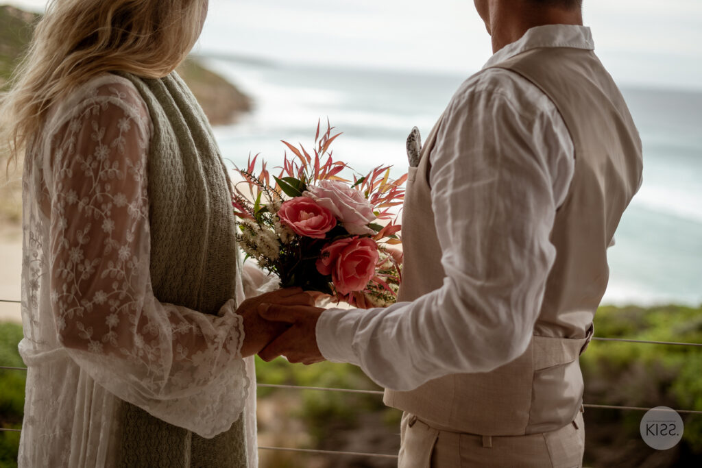 A couple holding hands beside a colourful bouquet