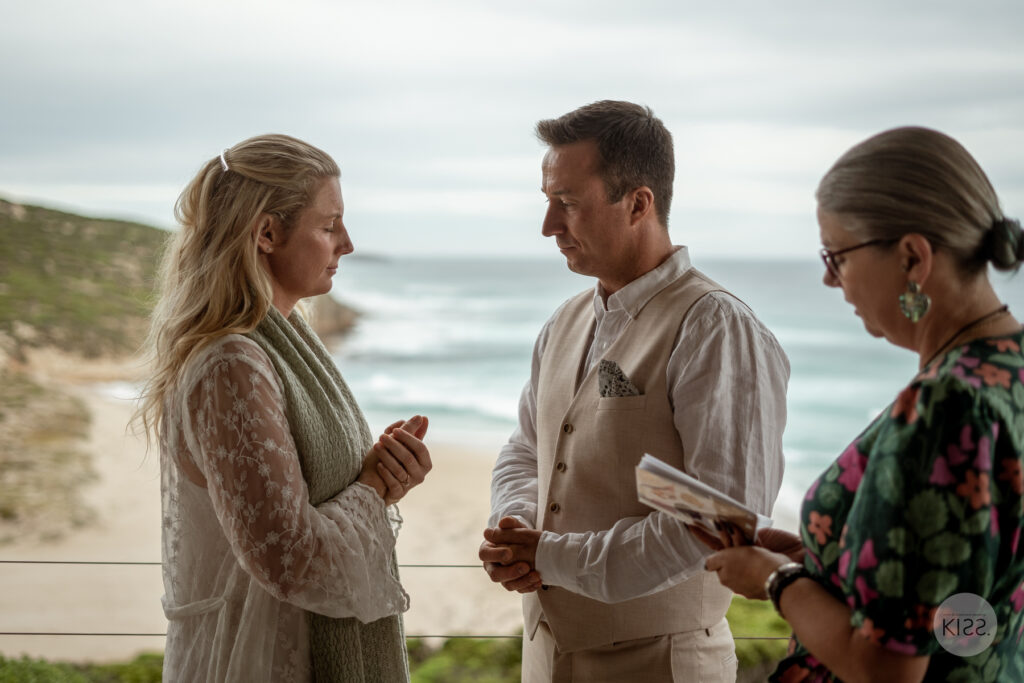 A celebrant guiding a couple through an ocean-view wedding ceremony