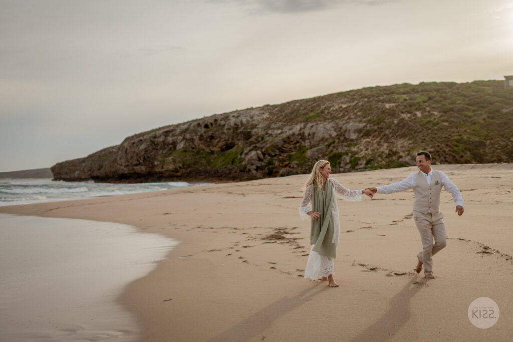 A wedding couple playing hand in hand on a sandy beach