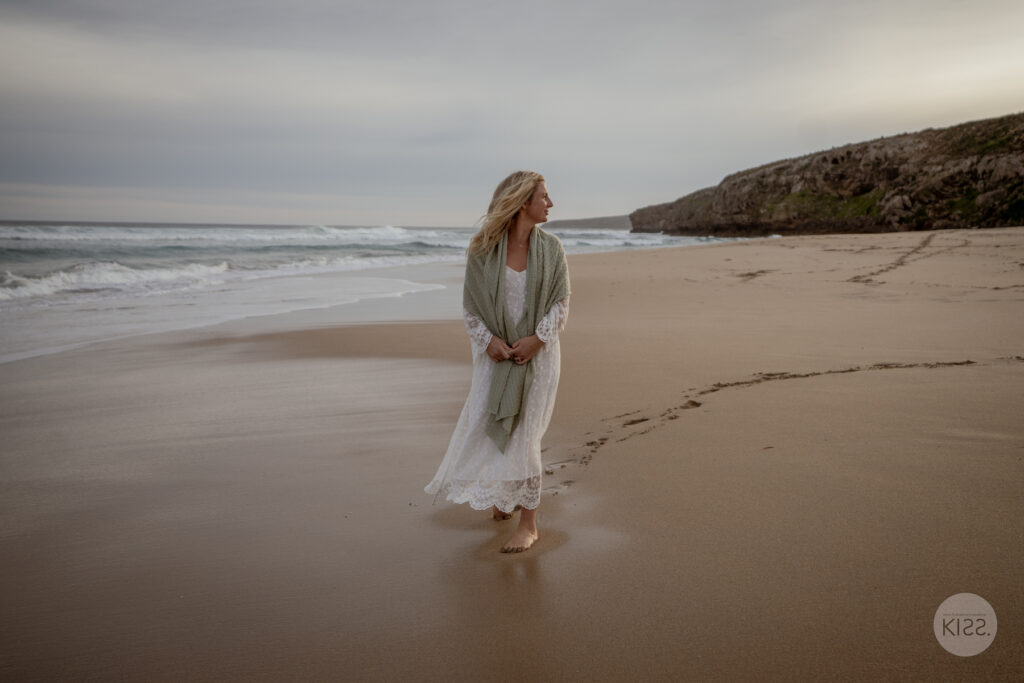 A bride walking along a wide sandy beach