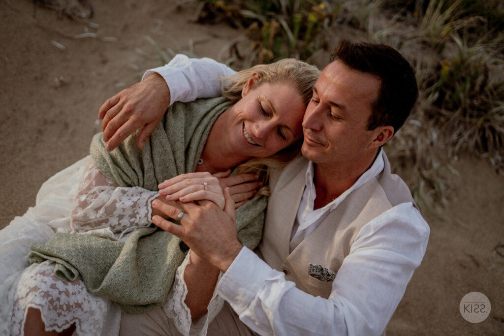 A couple sitting close together on the sand