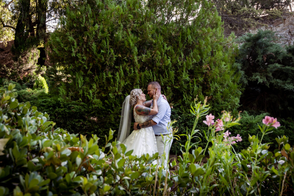 A wedding couple holding each other among flowers and trees