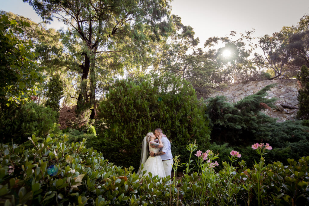 A wedding couple embracing among flowering garden plants