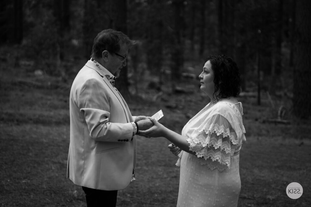 A groom reading his vows in the forest in black and white