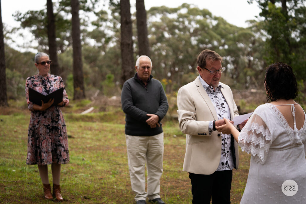 A groom reading his vows in a small forest ceremony