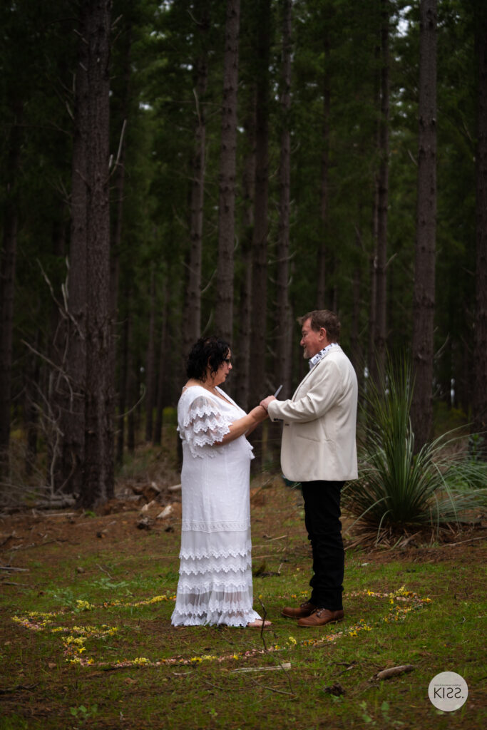 A couple holding hands during their forest wedding ceremony