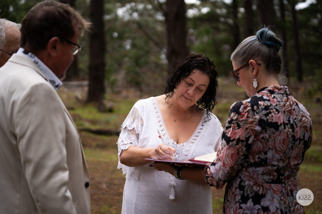 A bride signing the marriage register held by her celebrant