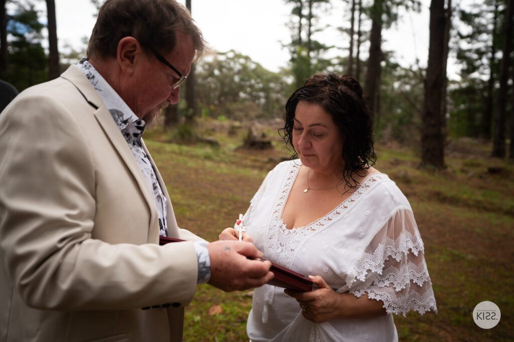 A groom signing the marriage register beside his bride