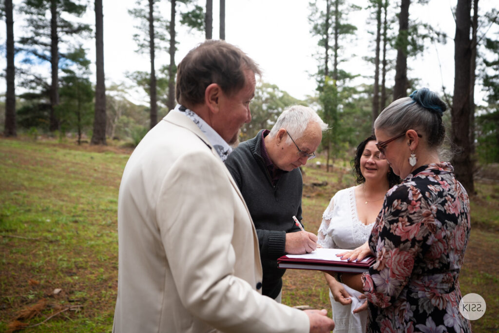 A witness signing the marriage register during a forest wedding