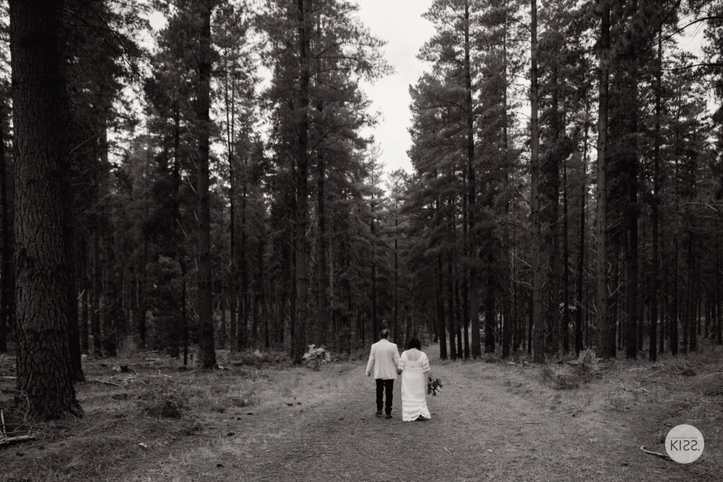 A wedding couple walking away along a forest path in black and white