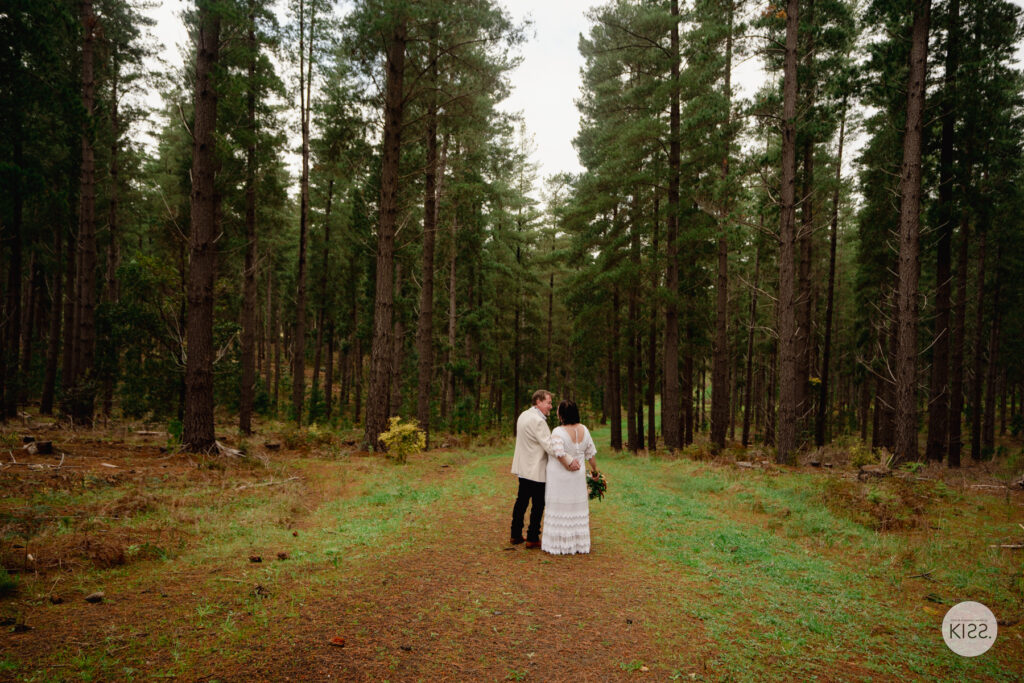 A wedding couple embracing among tall pines
