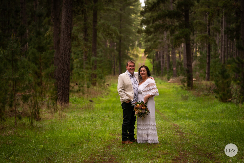 A wedding couple standing together on a green forest path