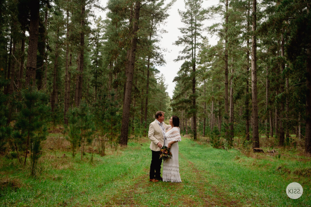 A couple kissing on a long forest path