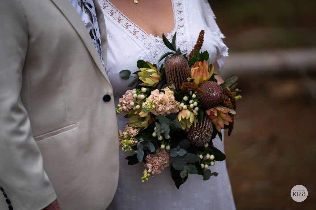 Native flower bouquet beside a bride's white lace dress