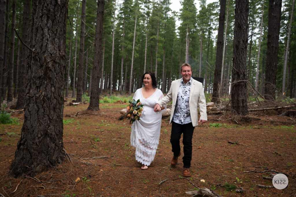A newly married couple walking along a forest path