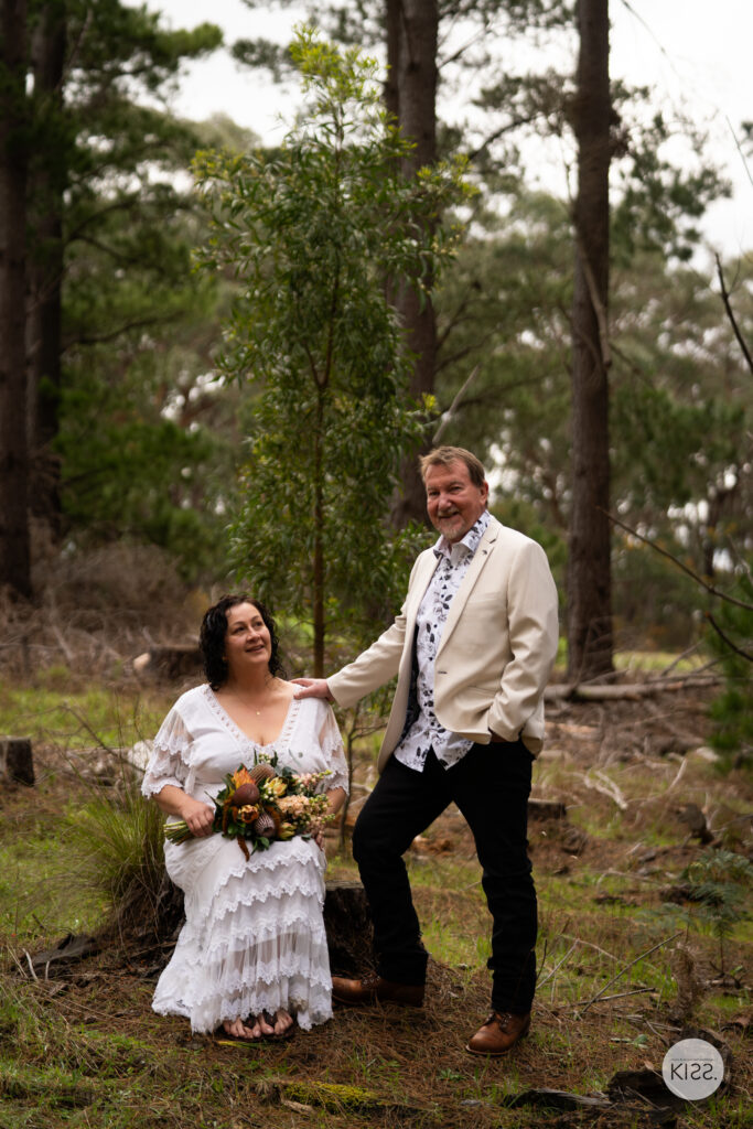 A wedding couple standing together on a forest path