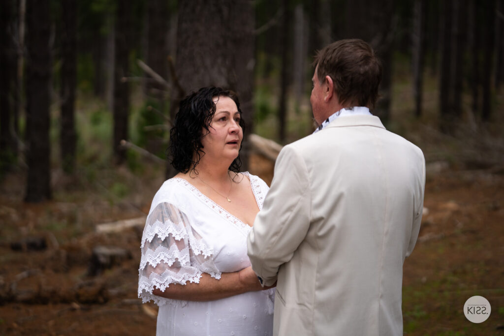 A bride smiling at her groom while holding his hands