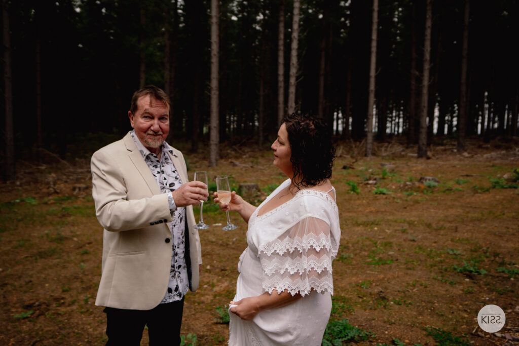 A wedding couple making a toast after their forest ceremony