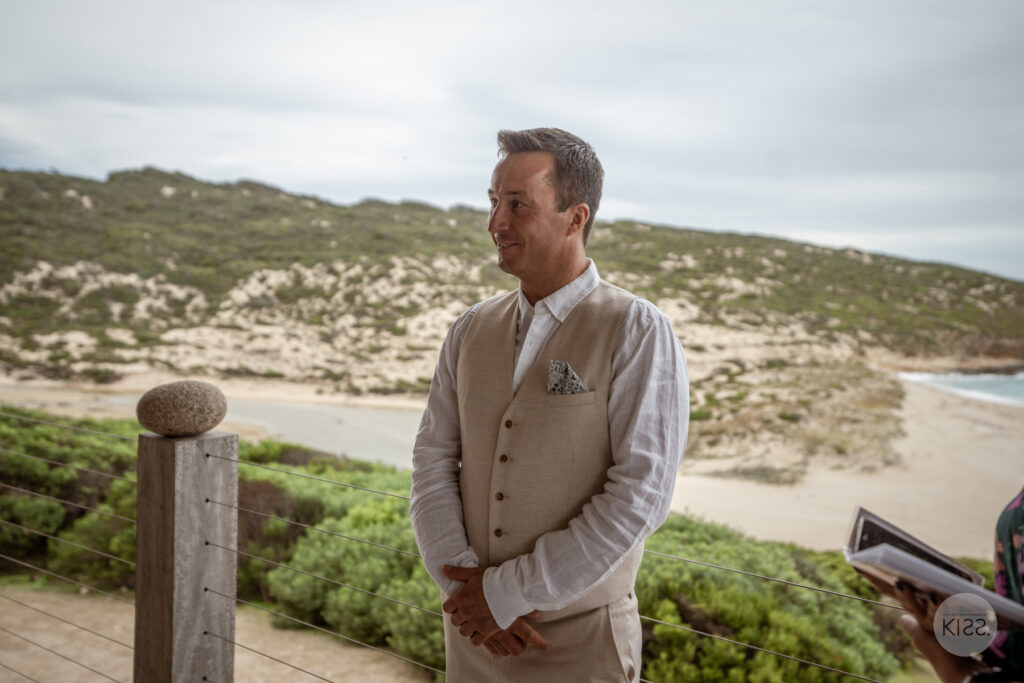 A groom waiting for the ceremony on an ocean-view deck