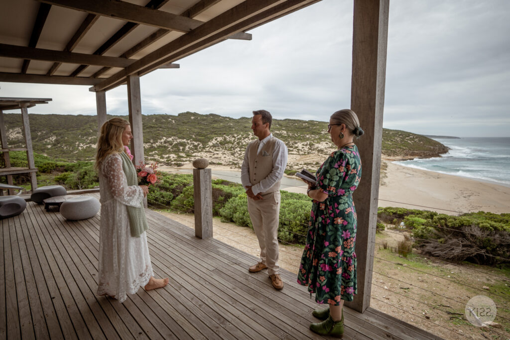 A celebrant conducting a wedding on a coastal deck