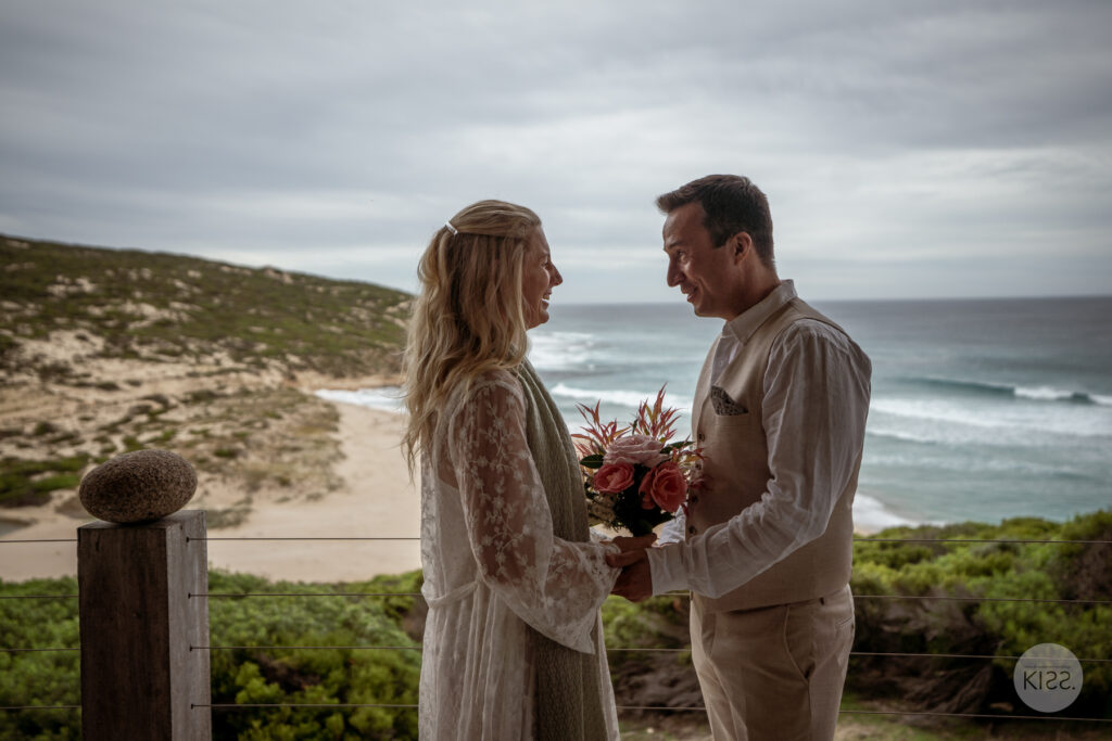 A couple holding hands during their ocean-view wedding ceremony